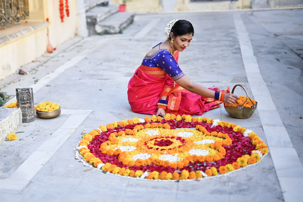 Indian woman in sari making floral Rangoli in the courtyard