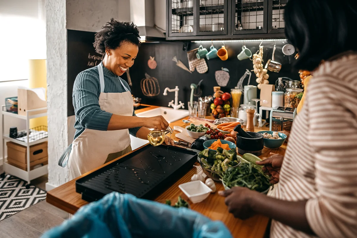 Smiling woman cutting eggplant vegetable in kitchen