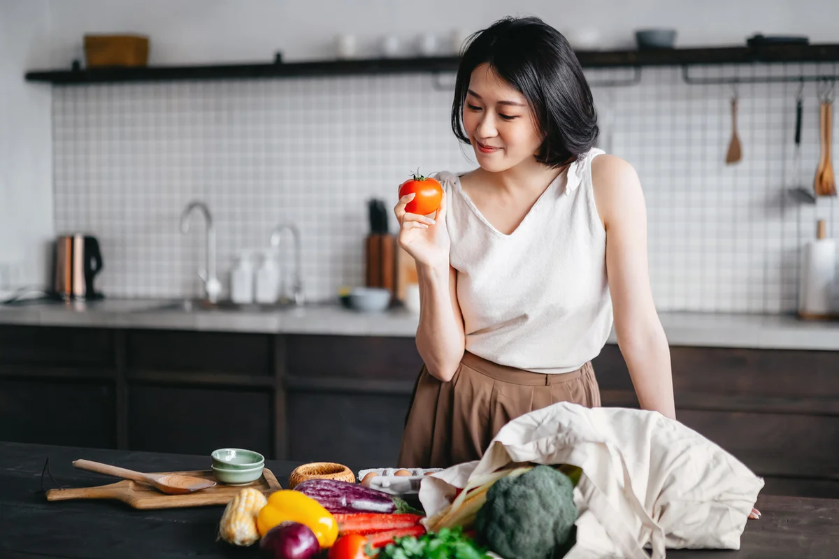 woman coming home from grocery shopping and taking out fresh fruits and vegetables