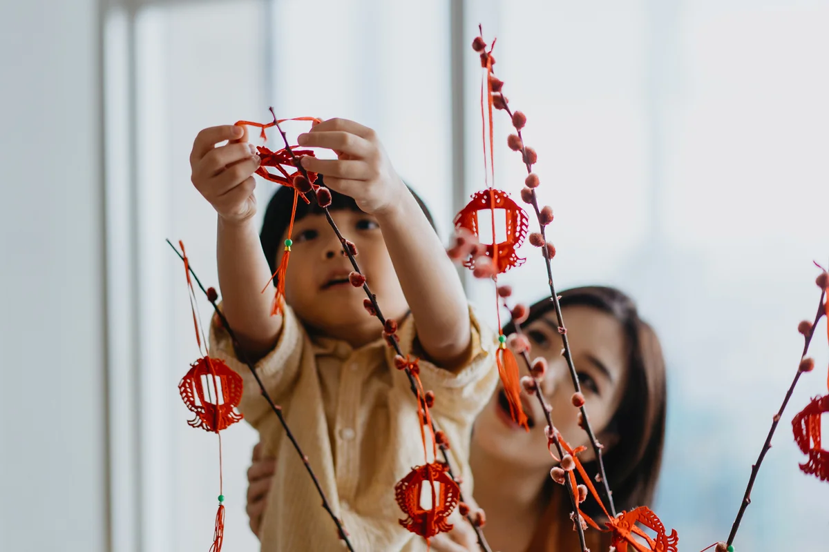 Chinese boy helping mother to hang Chinese New Year decoration