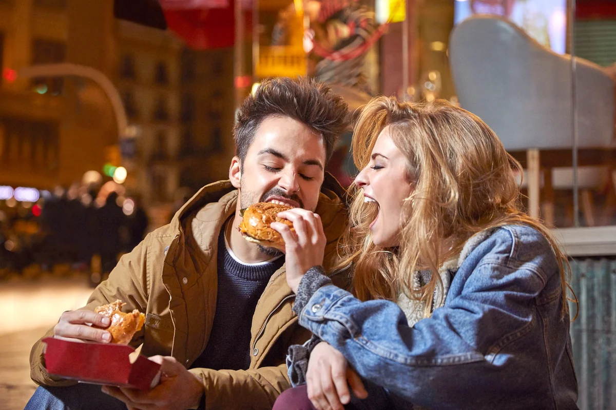 Couple eating burgers outside at nigh time