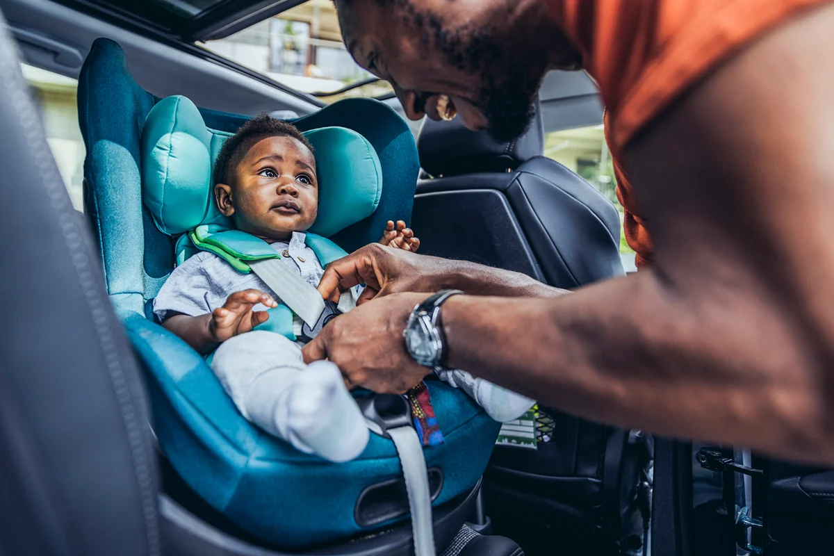 Father fastening seat belt of son in car