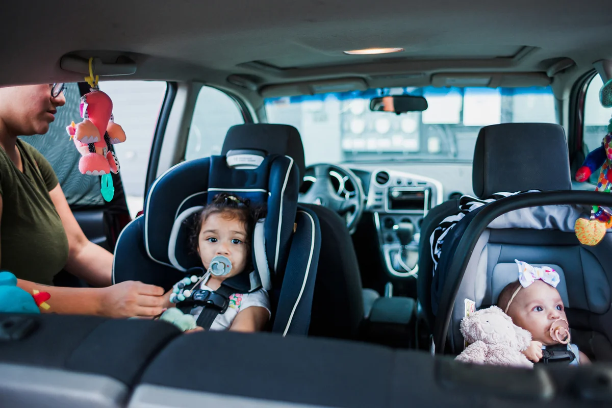 Mother Buckling Her Babies Into Carseats for Roadtrip
