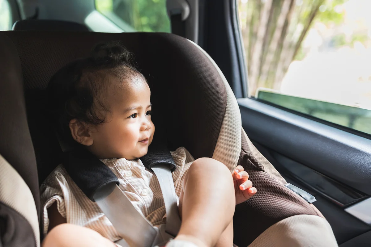 Toddler girl sitting in car seat and looking through window