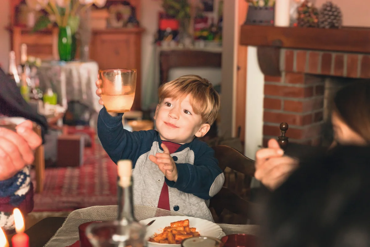 Young boy holding his glass to cheer at Thanksgiving table