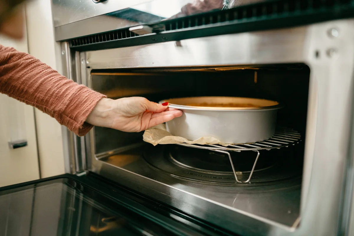 Woman putting cheesecake in the oven