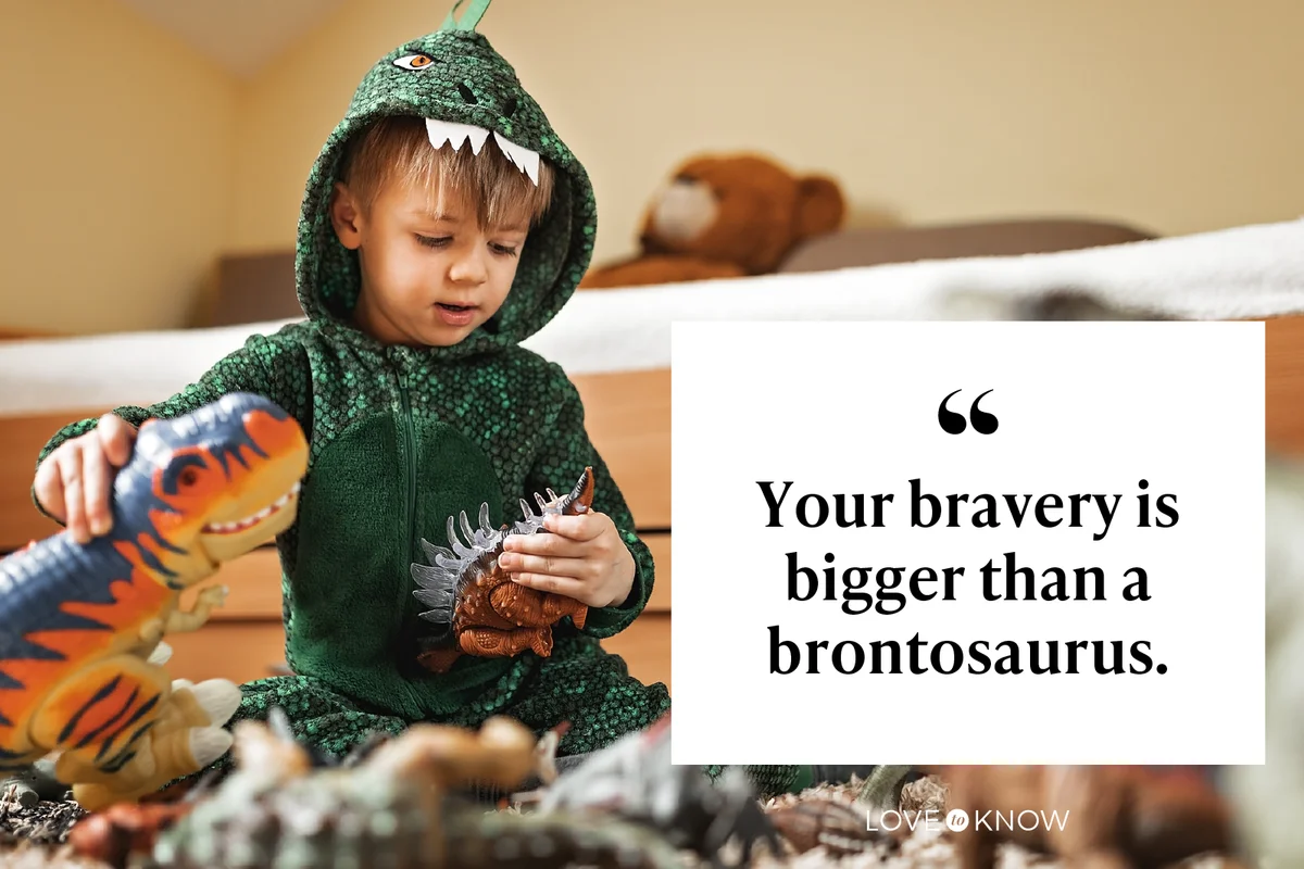 Toddler boy in a dinosaur costume playing with his dinosaurs
