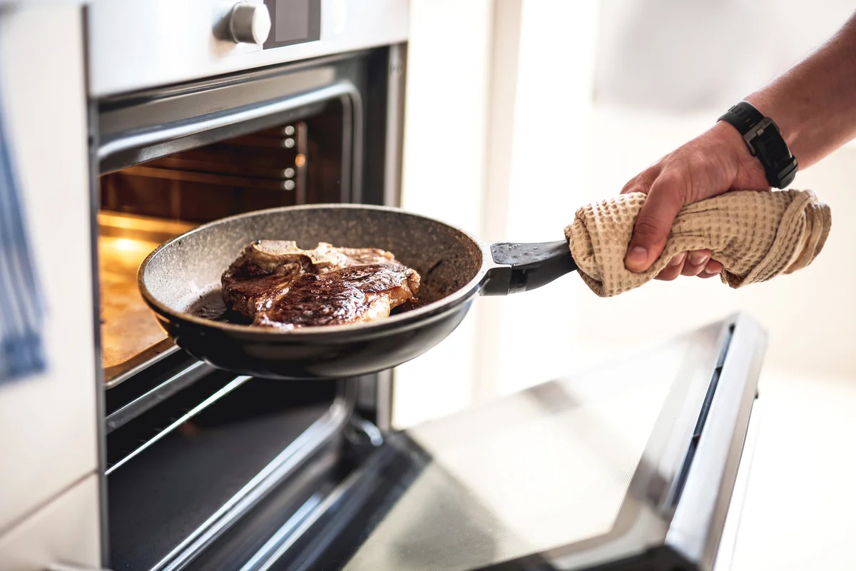 Man putting meat in oven while cooking dinner