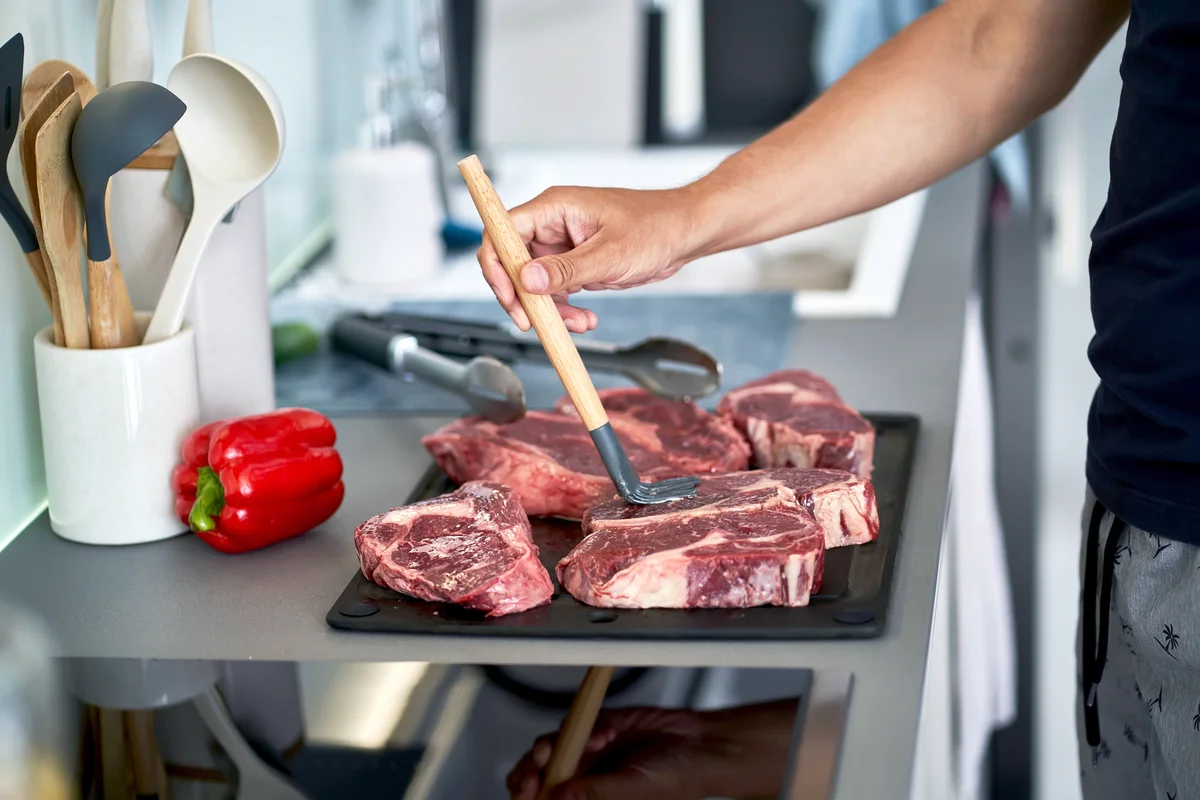 Man seasoning meat steaks before cooking