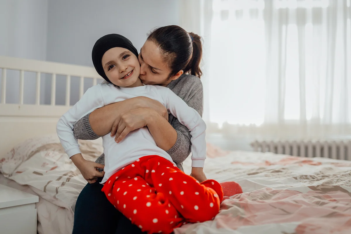 Mother hugs and kisses her child with cancer