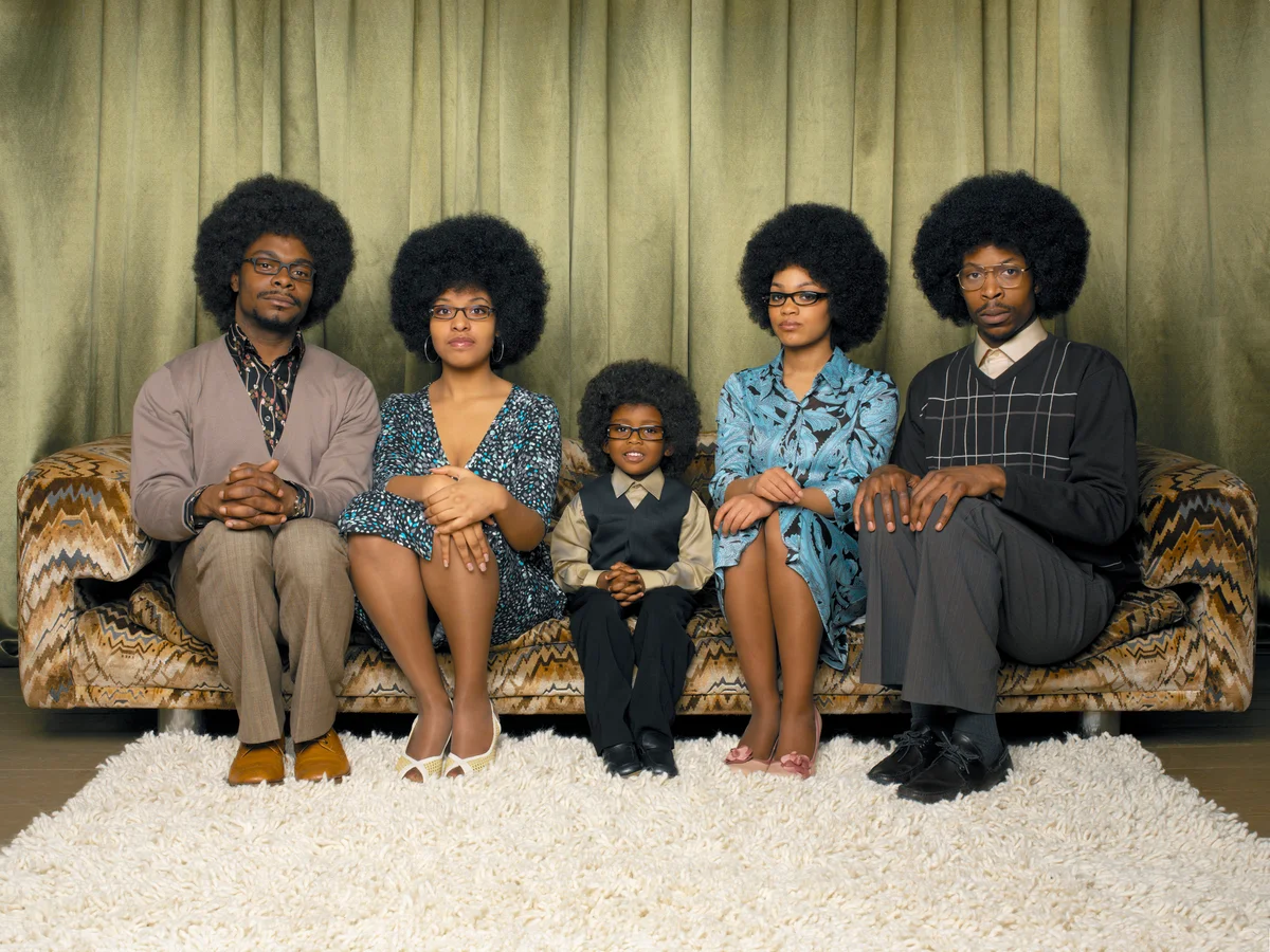 Family sitting on sofa, smiling, portrait