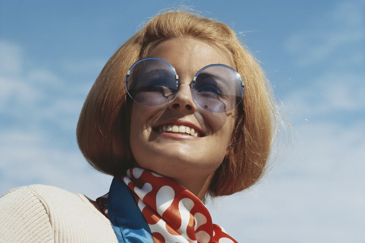 Young woman wearing sunglasses, smiling, close-up