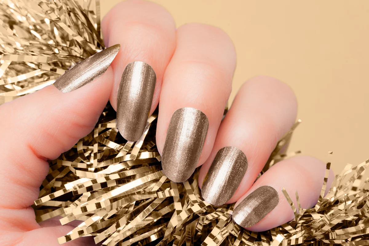 Female hand with champagne nails hold beige textured decoration on beige background