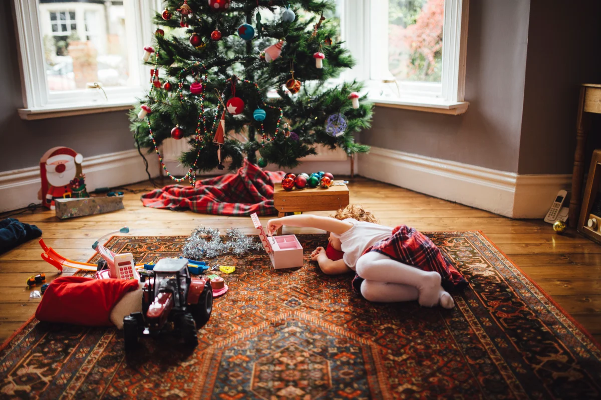 Little Girl Playing on Christmas Day with christmas tree in the back