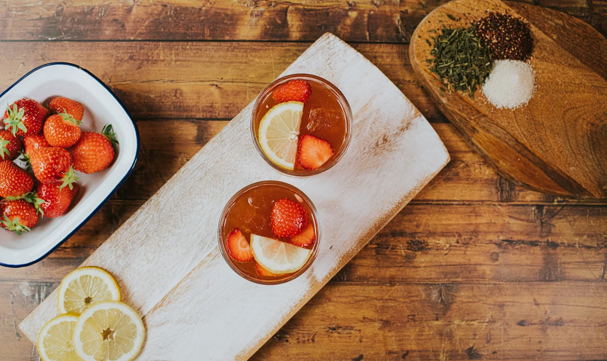 Two glasses on a chopping board, garnished with lemons and strawberries