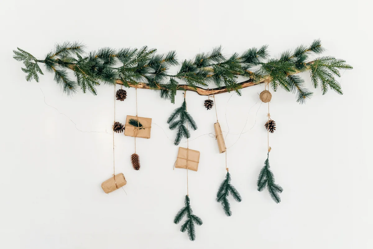 Christmas tree branch with a garland and gifts on the wall