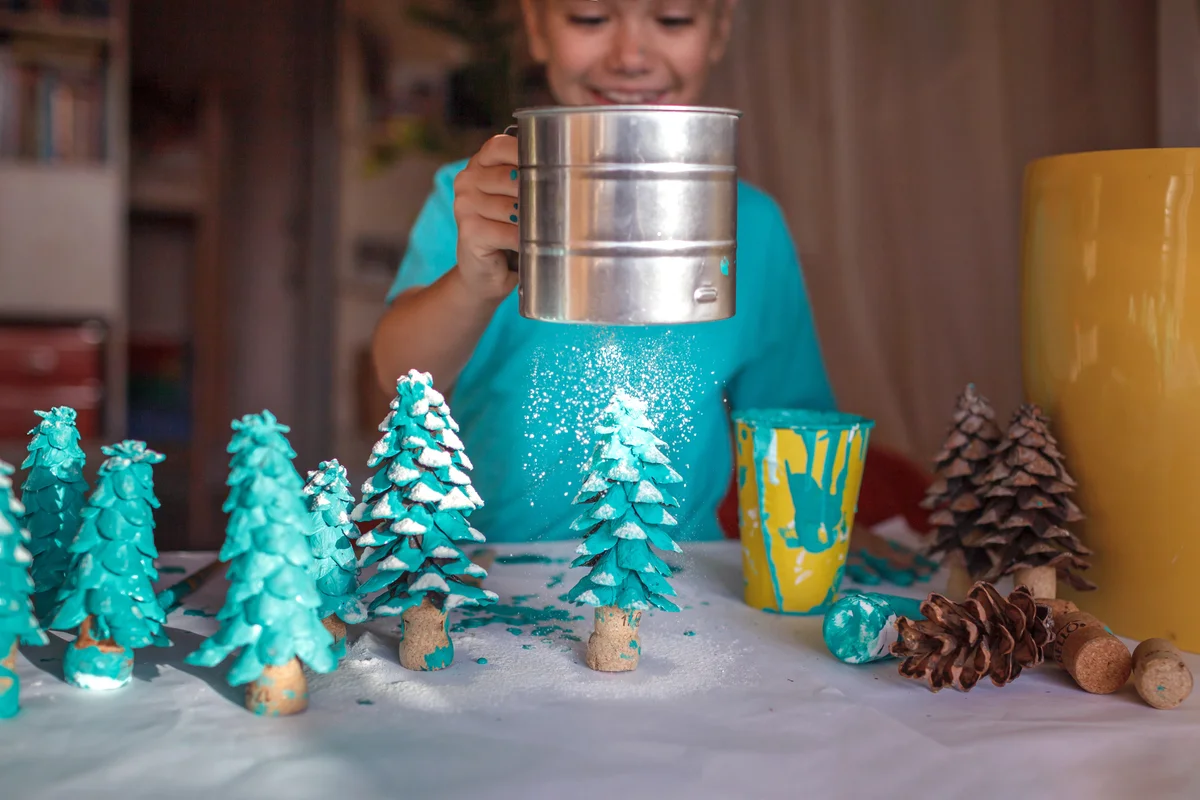 Little girl making Christmas trees out of pinecones