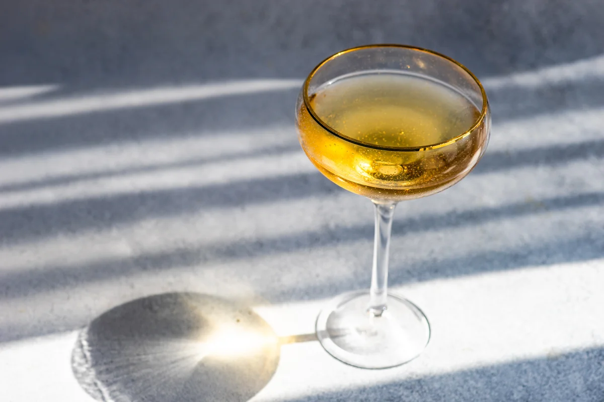 Champagne coupe of white wine on a table in sunlight