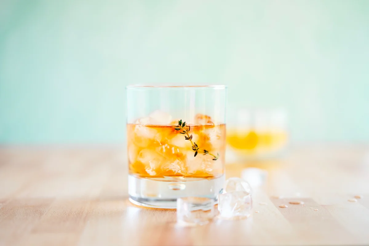 Glass of cocktail on wooden table on blue background