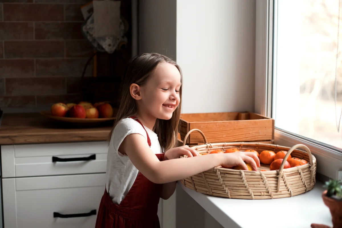 Little cute girl taking fruits from the tray at home