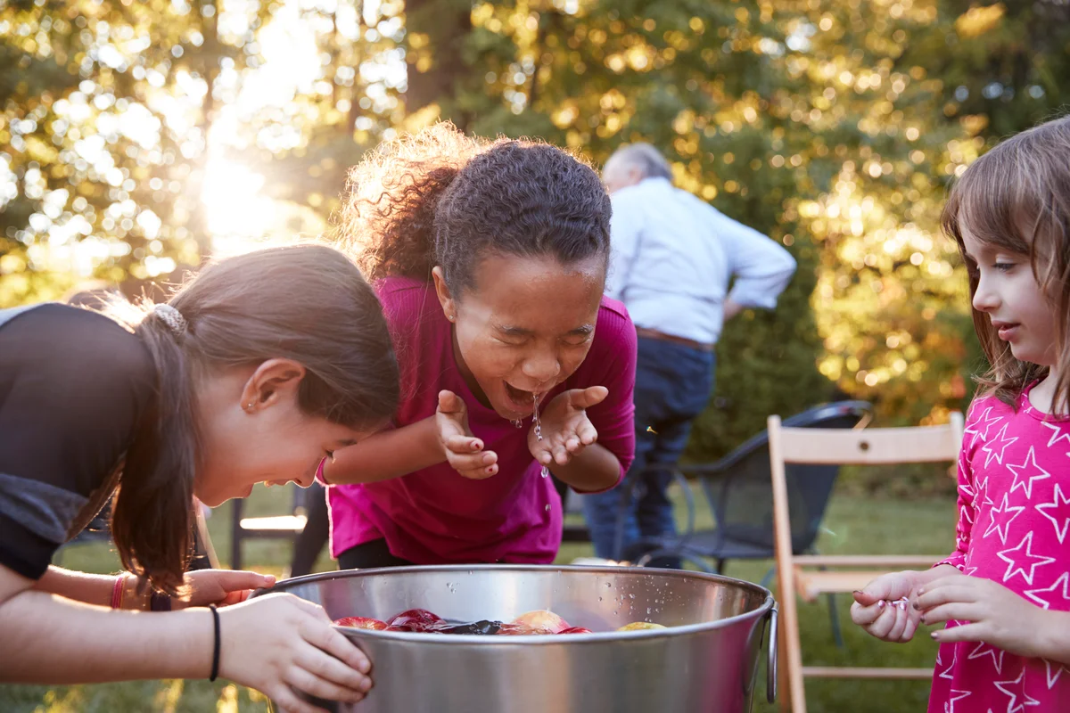 Three young girls apple bobbing at a backyard party