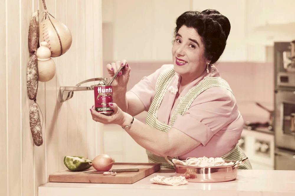 50's woman opening tin can while preparing food