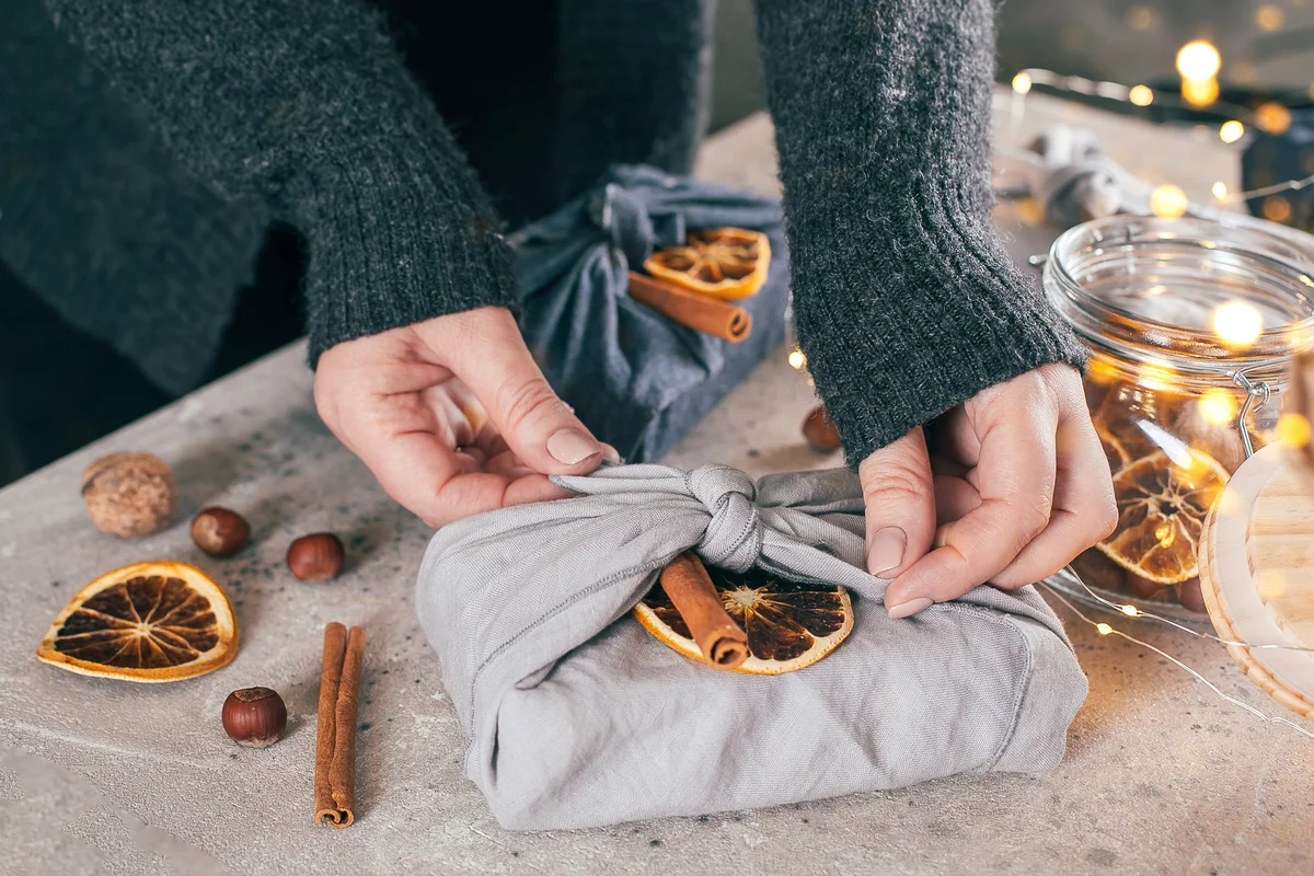Woman wrapped gift in fabric with organic dry orange