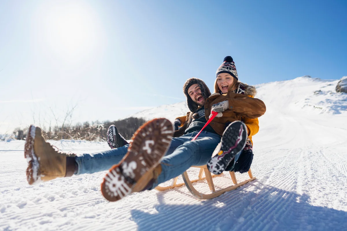 Young couple in love sledding and having fun on the snow