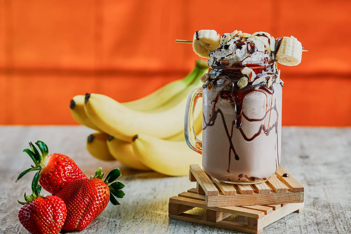 Chocolate smoothie with choco syrup and branch of bananas