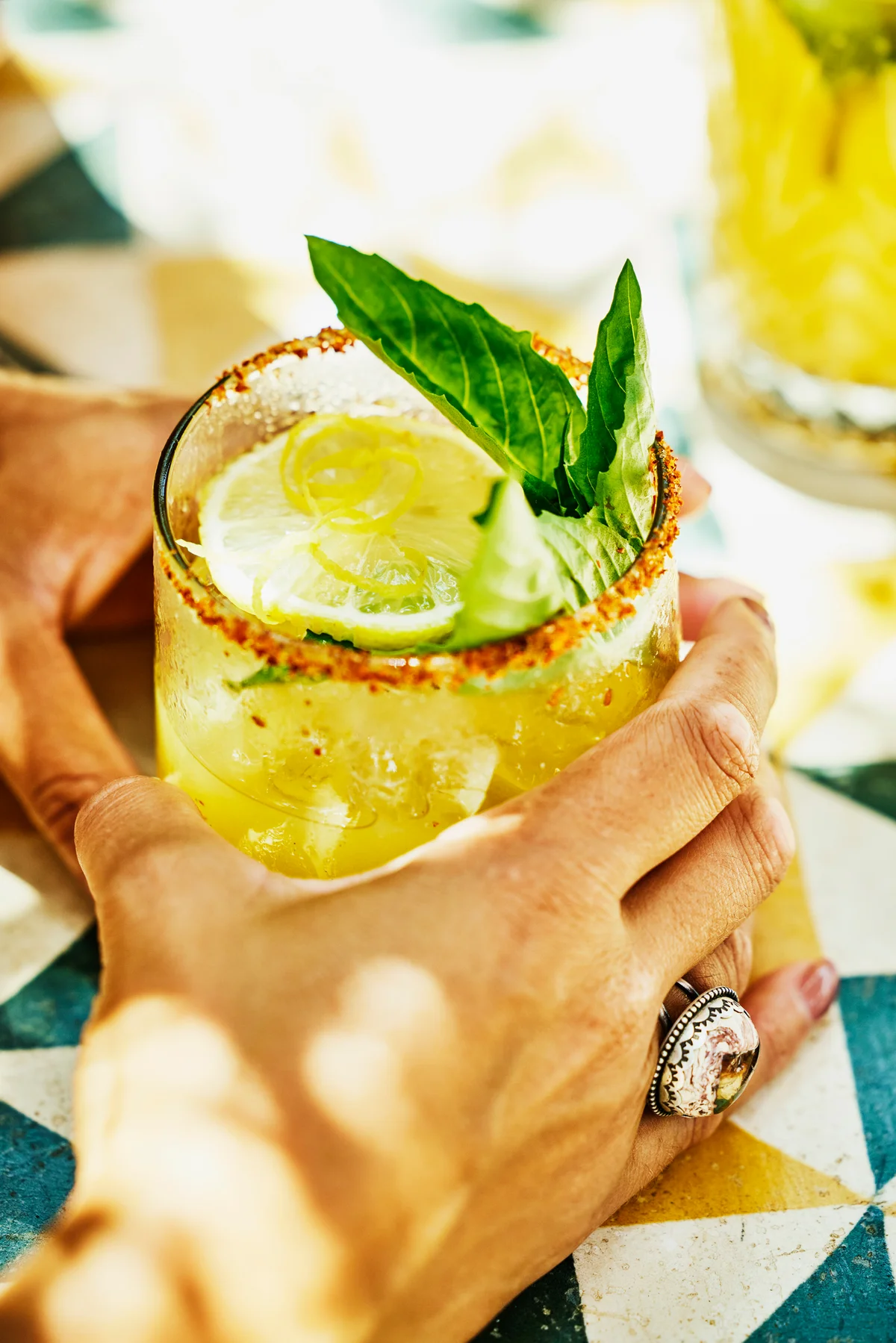 woman's hands holding margarita at table in beach cafe