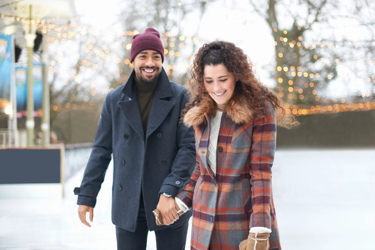 Couple on ice rink holding hands smiling