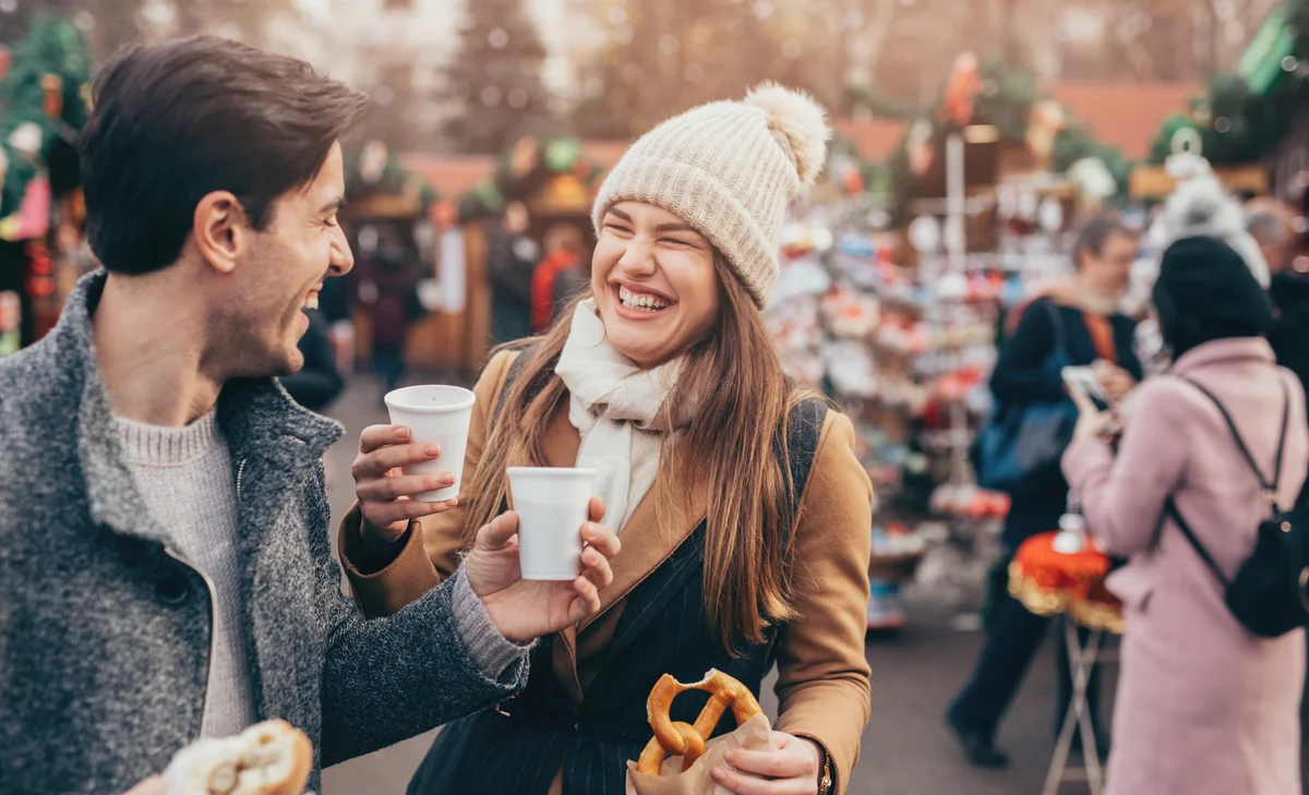 Couple drinking hot wine and eating pretzels at the Christmas market