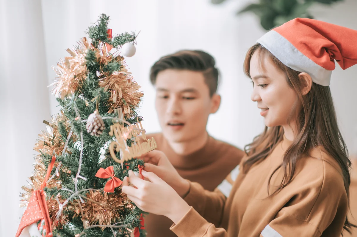 young couple celebrating christmas by decorating tree