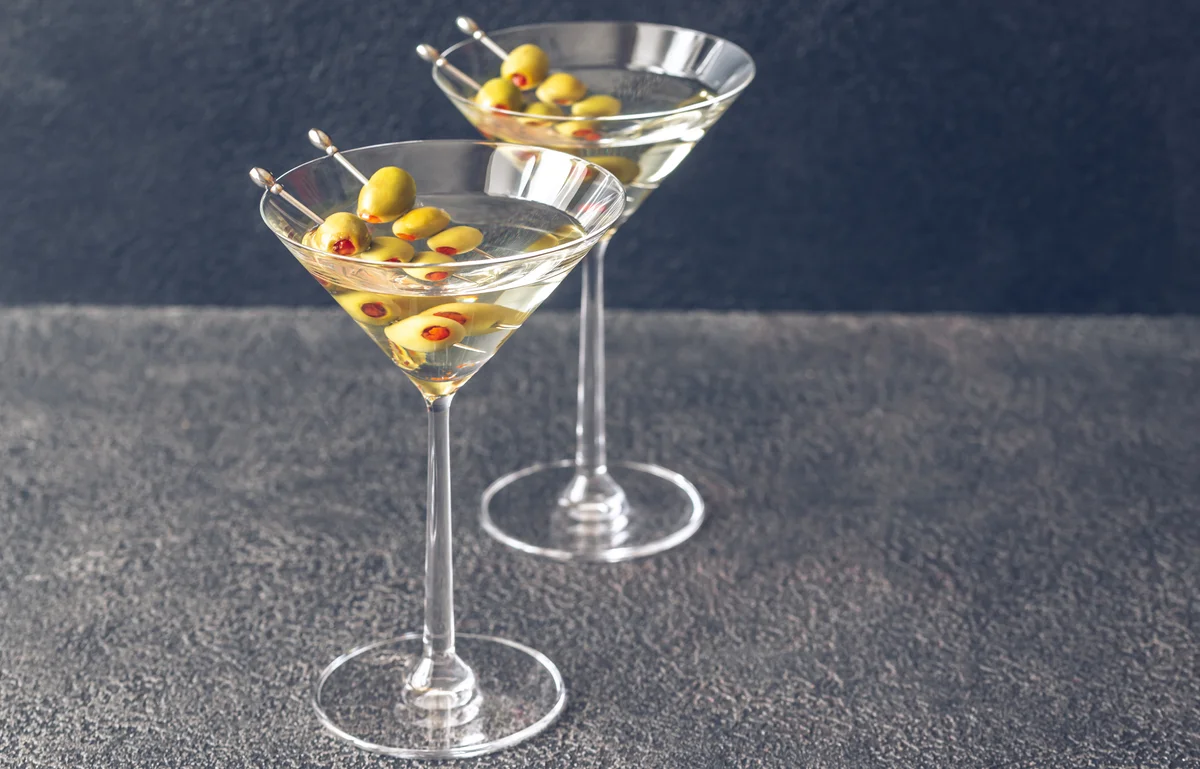 Two glasses of martini cocktail garnished with green olives
