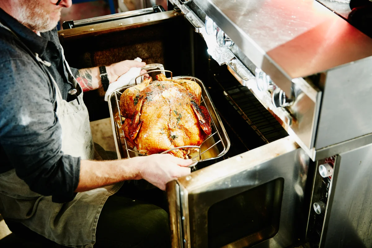 Man pulling cooked turkey out of oven