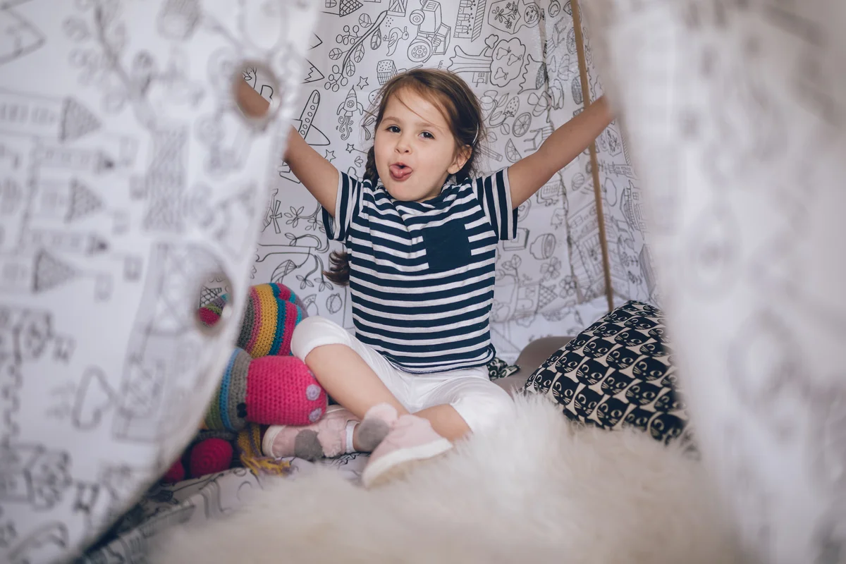 Playful child sitting in a fort at home