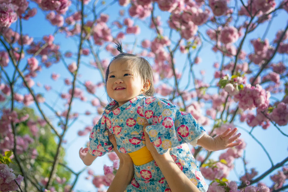 Mom having fun with her baby daughter in Cherry blossoms