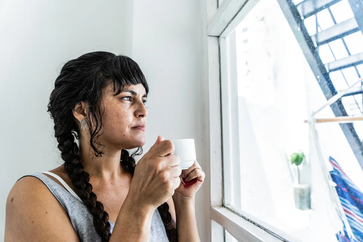 woman with tea looking out a window