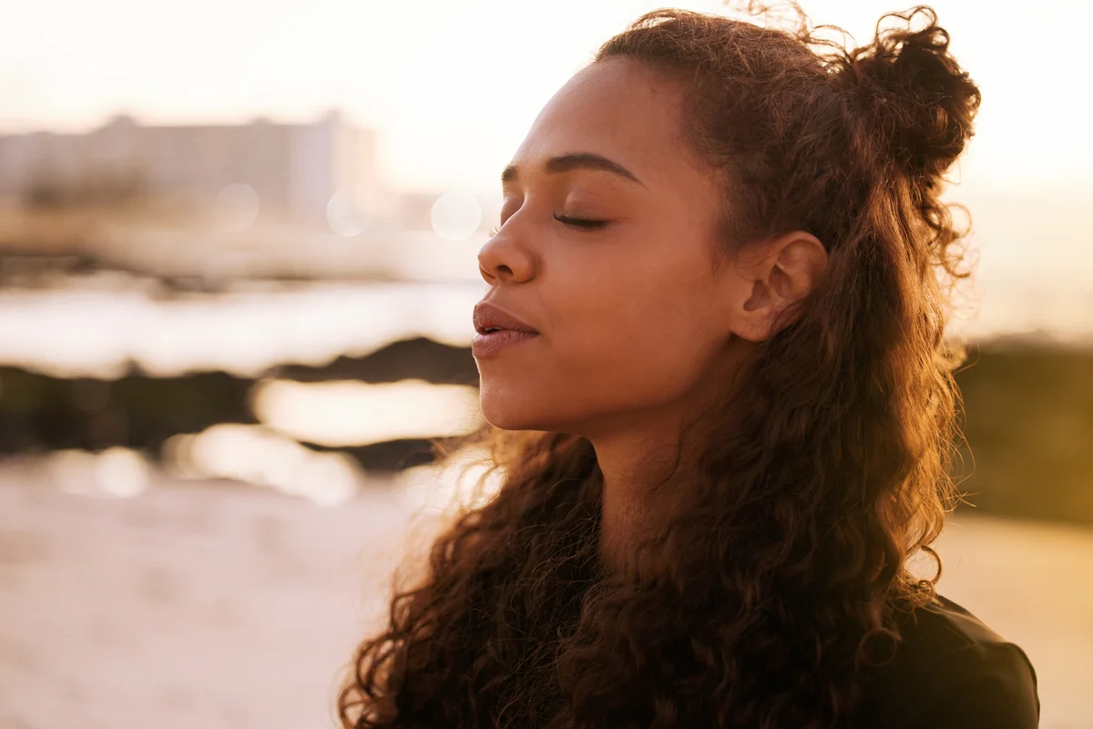 woman at a beach taking a deep breath