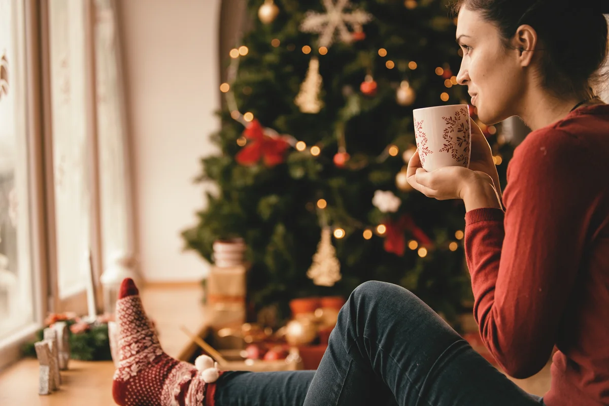 woman sipping tea by the Christmas tree