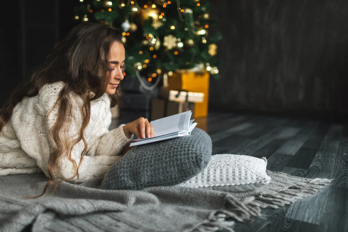 woman reading next to the Christmas tree