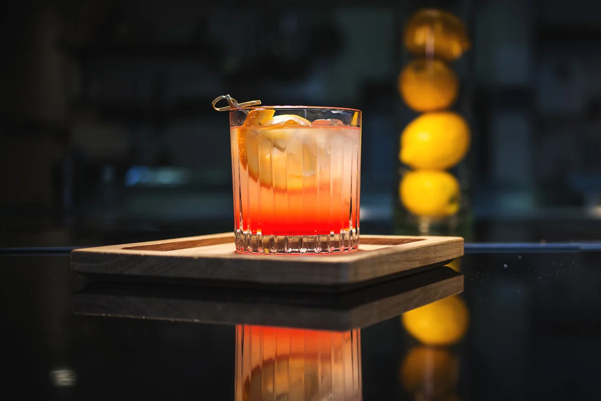 Old fashioned cocktail on the bar, on a wooden tray with oranges in the background