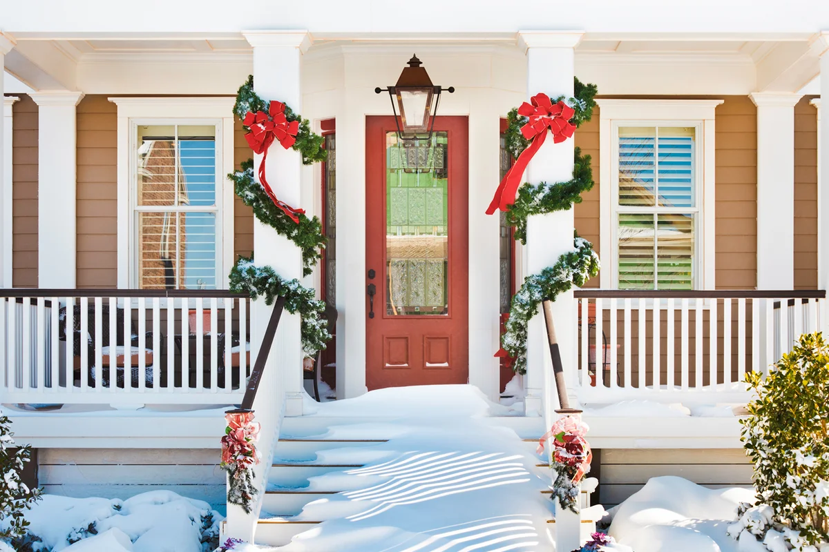 Inviting Christmas front doorway with snow on porch stairs