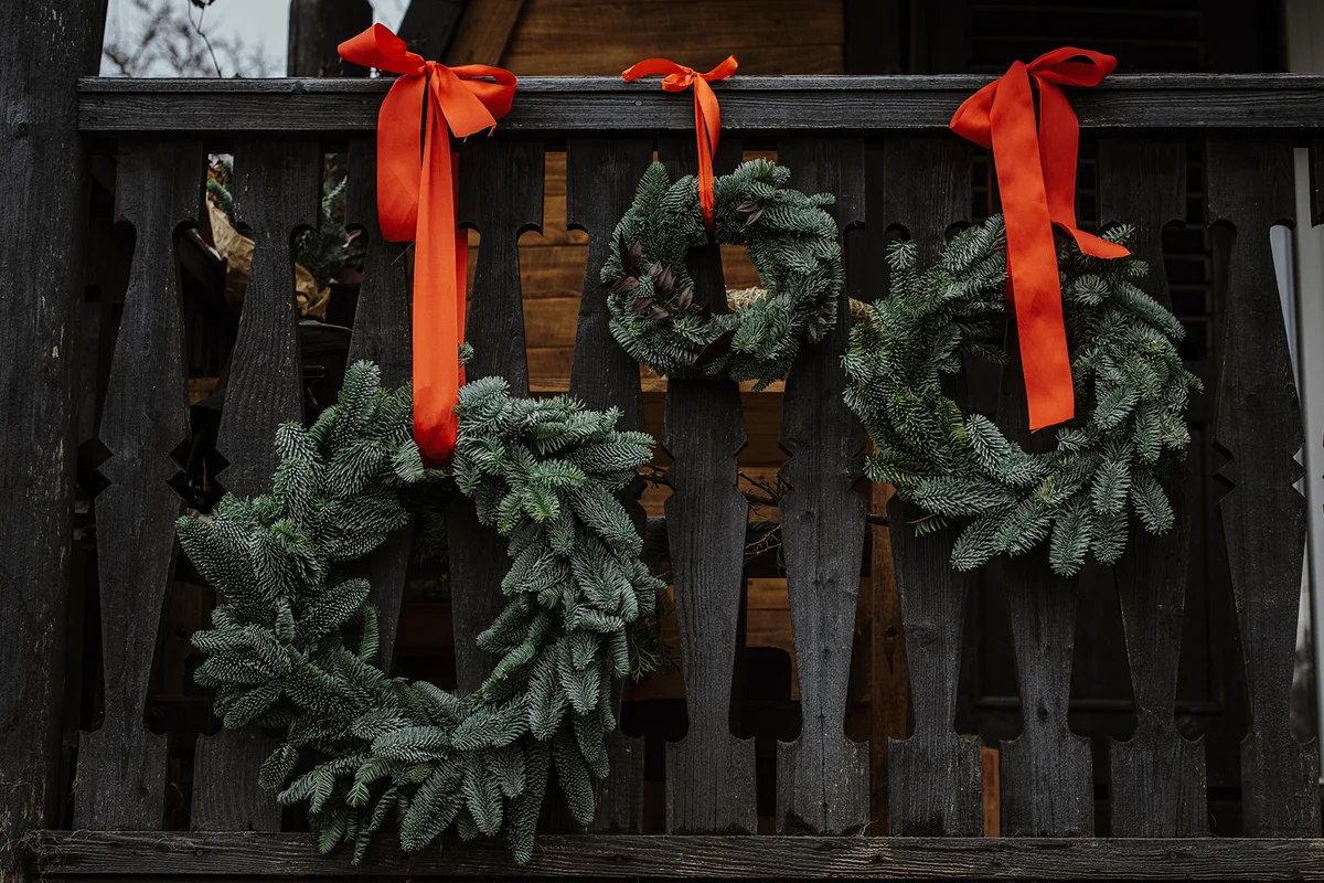 A natural setup with Christmas pine wreaths outside a wooden house