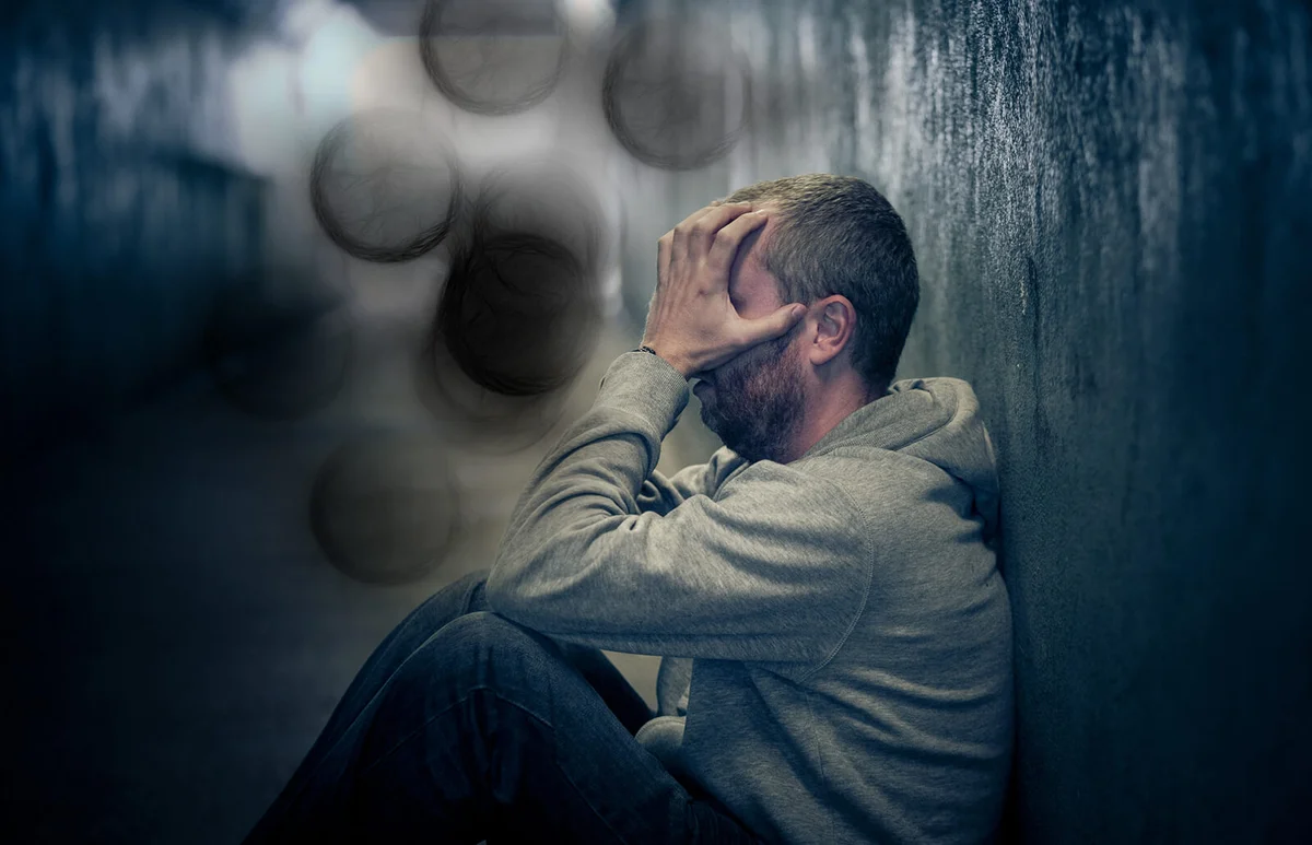 Young homeless caucasian male sitting in dark subway tunnel
