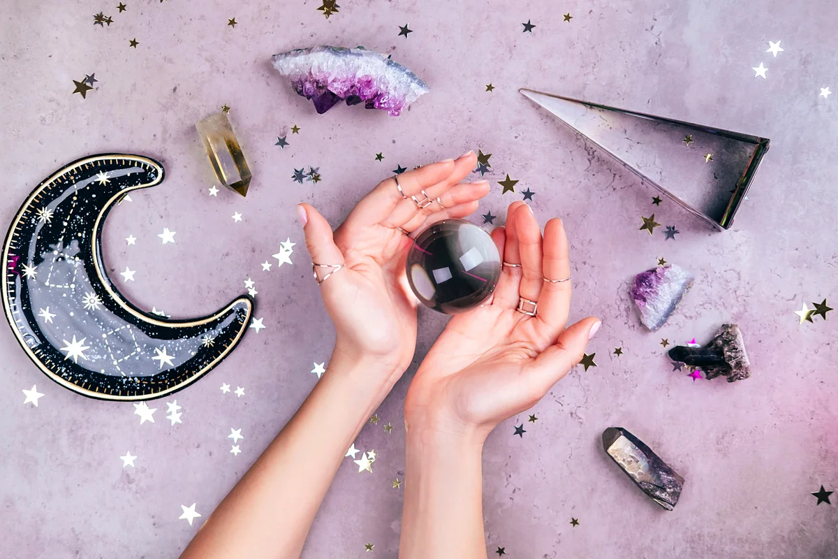 Hands with rings on fingers are holding crystal ball near esoteric set