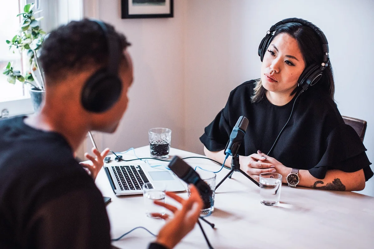 Bloggers talking through microphones and headphones sitting at table