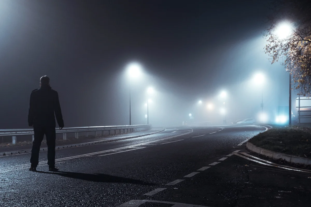 Man standing on foggy empty road