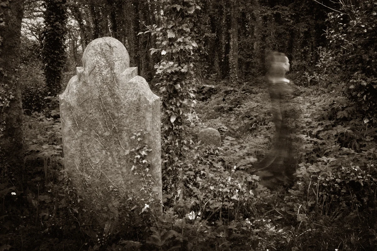 Ghostly image in front of a gravestone in a graveyard