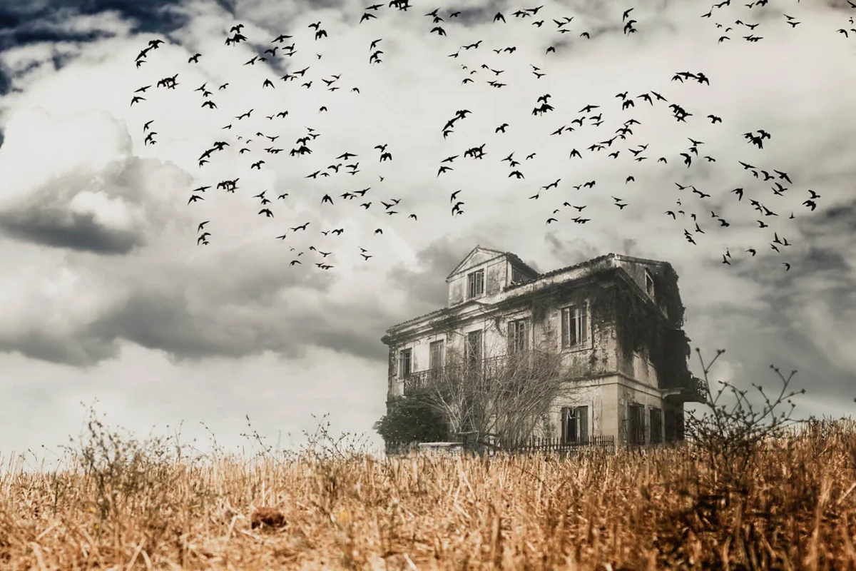 Man walking in a field towards a haunted house
